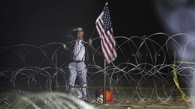 Mu s vlajkou USA na americké stran hranice u Tijuany (15. listopadu 2018)