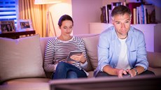 Lidé u televize koukají do mobilu nebo tabletu Lidé u televize koukají do mobilu nebo tabletu