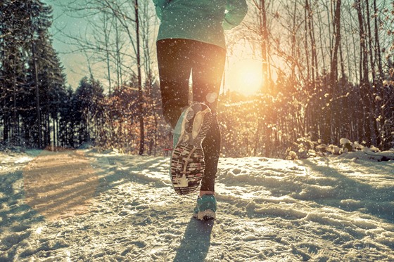 Woman Running at snowly winter under sunlight.