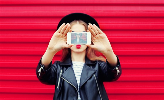 Fashion glamour woman makes self portrait on smartphone blowing