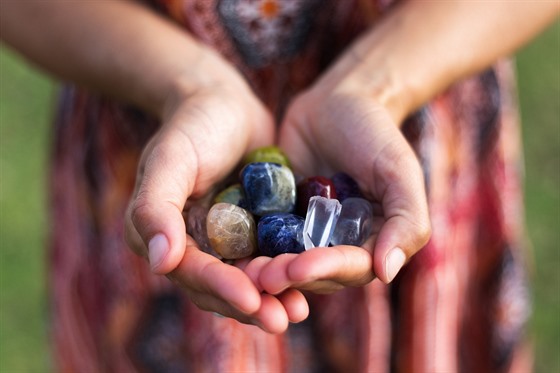 A young woman carefully holds a selection of vibrant gemstones as they reflect the soft sunlight.