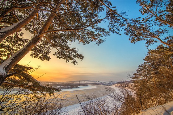 Landscape with sunset on frozen river and forest