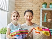 78027780 - beautiful young woman and child girl little helper are having fun and smiling while doing laundry at home.