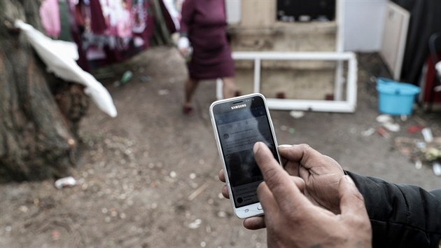 Mu z romsk komunity na pedmst Bobigny ukazuje na telefonu falenou zprvu o bl dodvce. (27. bezna 2019)