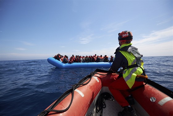 Migranti na gumovém lunu jsou osloveni pracovníky záchranných lodí Sea-Watch...