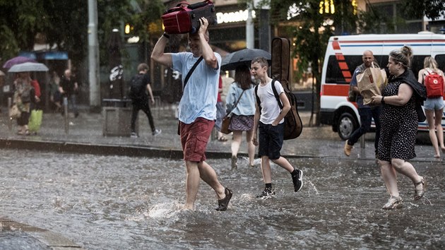 Lidé se utíkají před deštěm v Praze na Andělu. (6. června 2019)