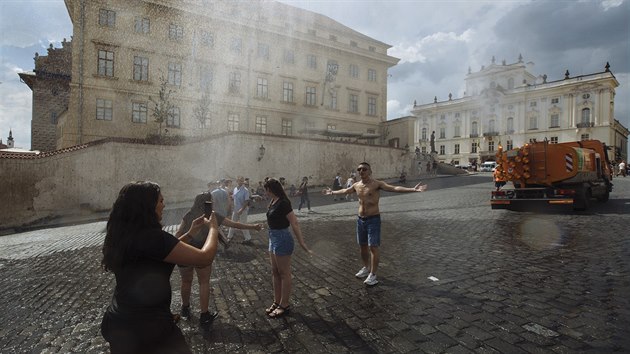 Turist i Praan se chlad dky kropcmu vozu na Hradanskm nmst v Praze (15. 6. 2019).