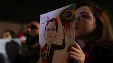 Demonstrantka s transparentem namíeným proti prezidentovi Bolsonarovi pi...