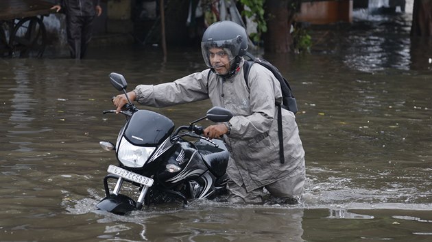 Mu v Ahmadabadu v Indii vede motocykl zaplavenou ulic. (10. srpna 2019)