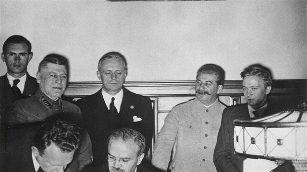 Vjaeslav Molotov podepisuje nmecko-sovtskou smlouvu o netoen. Vpozad pihl Joachim von Ribbentrop (v ernm) a Stalin (druh zprava).