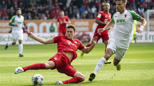 Benjamin Pavard (vlevo) z Bayernu Mnichov hraje balon, sth jej Florian Niederlechner z Augsburgu.