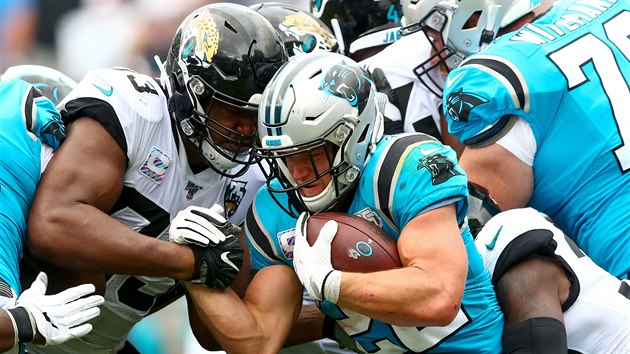 Christian McCaffrey (v modrm) z Carolina Panthers se tla mezi obrnci Jacksonville Jaguars.