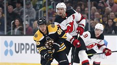 David Pastrák z Bostonu ujídí za pukem, za ním Travis Zajac z New Jersey.