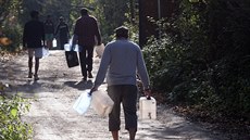 Migranti v uprchlickém táboře Vučjak v Bosně nesou kanystry s vodou. Úřady jim... Migranti v uprchlickém táboře Vučjak v Bosně nesou kanystry s vodou. Úřady jim...