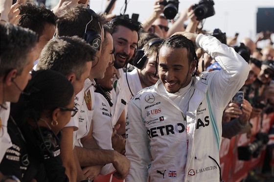 Kolegové z Mercedesu gratulují jezdci Lewisu Hamiltonovi (vpravo) k zisku...