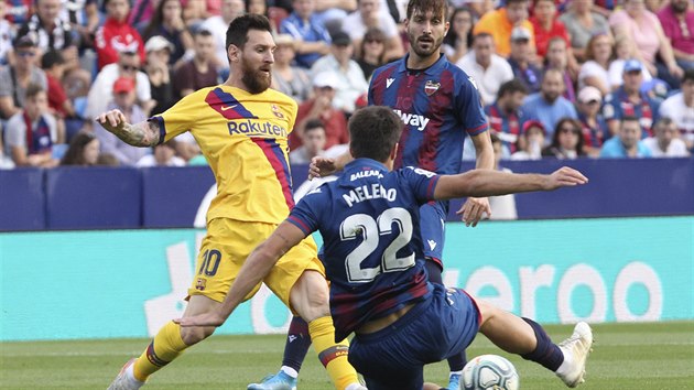 Barcelonsk Lionel Messi (ve lutm) se sna hrt balon, brn mu v tom Gonzalo Melero z Levante.