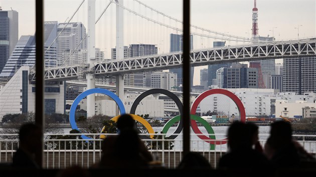 Lidé sledují obří olympijské kruhy v Tokiu. Lidé sledují obří olympijské kruhy v Tokiu.