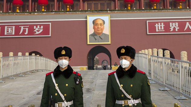 Policist s roukami ped podobiznou Mao Ce-tunga v Pekingu (27. ledna 2020)