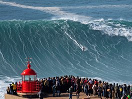 Publikum sleduje brazilského surfae Rodriga Koxe v portugalském Nazaré. Vlny...
