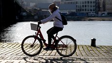 Žena v roušce projíždí po cyklostezce na náplavce u železničního mostu v Praze.... Žena v roušce projíždí po cyklostezce na náplavce u železničního mostu v Praze....