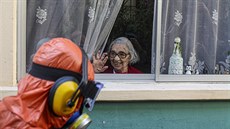 Seniorka zdraví pracovníka, který provádí dezinfekci ulice v Santiagu, hlavním... Seniorka zdraví pracovníka, který provádí dezinfekci ulice v Santiagu, hlavním...