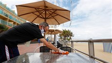 Číšník dezinfikuje stůl restaurace na pláži Las Canteras. (11. května 2020) Číšník dezinfikuje stůl restaurace na pláži Las Canteras. (11. května 2020)