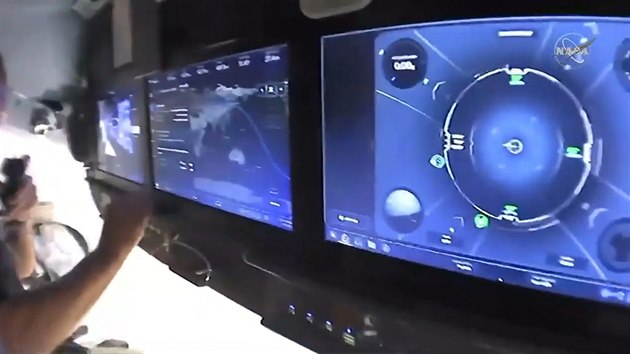 Displeje v lodi Crew Dragon na obn drze nkolik hodin ped pletem k ISS. Zleva: video z penosu, pozice lodi nad Zemkoul, pohled na pipojovac systm.