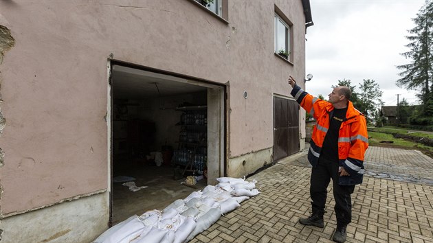 Petr Večeřa z Břevence u svého domu poničeného bleskovou povodní. Na fasádě jsou vidět díry způsobené naplavenými kládami. Nejvyšší z nich se nachází až pod oknem v prvním patře.
