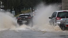 Auta pejídjí zatopenou silnici u ivotic u Nového Jiína. (19.6.2020)
