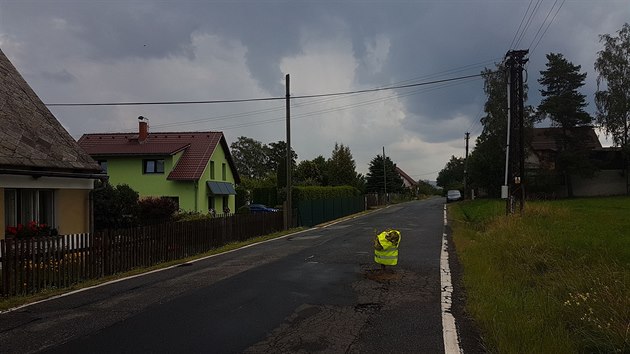 Na díru v zemi upozorňuje strom v reflexní vestě.