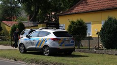Zpoza uzavřené vstupní branky, kterou hlídali policisté v uniformě, se několik... Zpoza uzavřené vstupní branky, kterou hlídali policisté v uniformě, se několik...