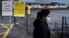 Žena v roušce prochází kolem hlavní promenády v irském městě Galway, která byla... Žena v roušce prochází kolem hlavní promenády v irském městě Galway, která byla...