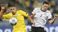 Vitalij Mykolenko z Ukrajiny (vlevo) a Nmec Julian Draxler bhem utkání Ligy...