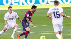 Barcelonský Lionel Messi proniká s míem u nohy mezi bránícími hrái Realu...
