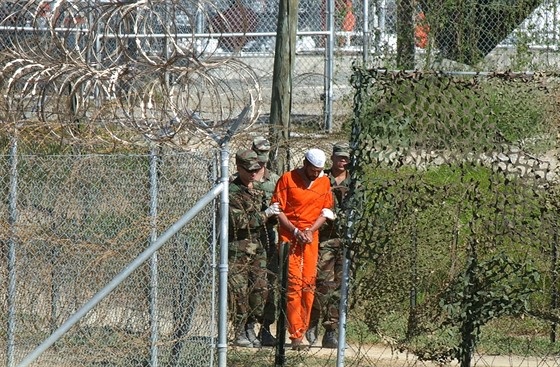 Amerití vojáci vedou trestance ve vznici Guantánamo. (1. bezna 2002)