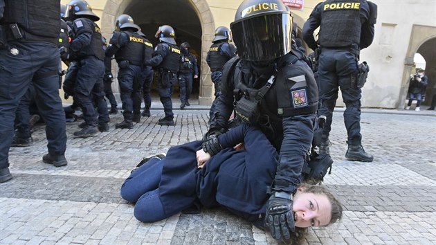 Policista pacifikuje enu na Staromstskm nmst v Praze, kde se konala demonstrace proti vldnm opatenm proti koronaviru. (7. bezna 2021)