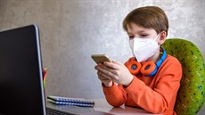 Chlapec hrající hry na telefonu během online výuky. Chlapec hrající hry na telefonu během online výuky.