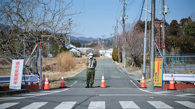Policista hlídá vjezd do jedné z ulic msta Okuma ve výluné zón v japonské...