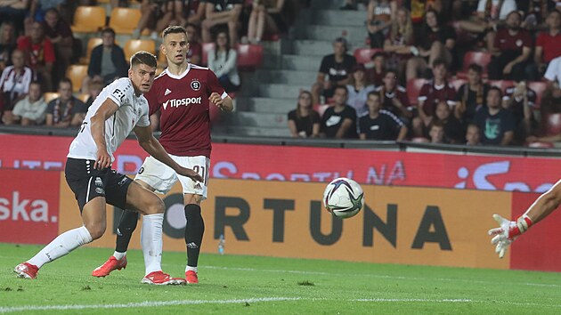 Jakub Pešek střílí druhou branku Sparty technickou střelou zpoza obránce Hradce Jana Mejdra (vlevo).