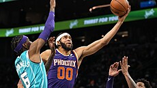 JaVale McGee (uprostřed) z Phoenixu bráněný Jalenem McDanielsem z Charlotte. JaVale McGee (uprostřed) z Phoenixu bráněný Jalenem McDanielsem z Charlotte.