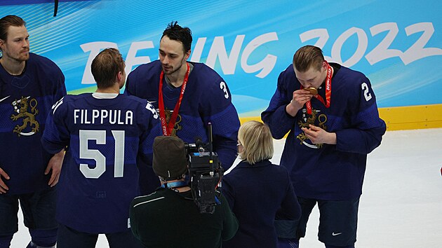 Finský hokejový obránce Ville Pokka (2) líbá zlatou olympijskou medaili. Vedle něj mezitím spoluhráči z obrany Niklasi Frimanovi (3) gratuluje kapitán Valtteri Filppula (51). Vlevo čeká další bek Mikko Lehtonen.
