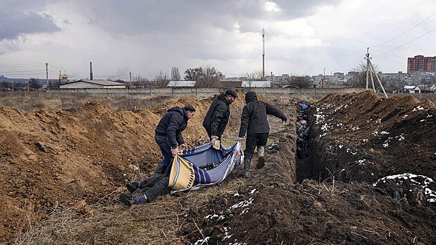 Mrtv tla jsou ukldna do masovho hrobu na pedmst Mariupolu (9. bezna 2022)