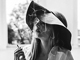 Zasnná dívka s cigaretou a okno, které jako by vedlo do jiného svta.
