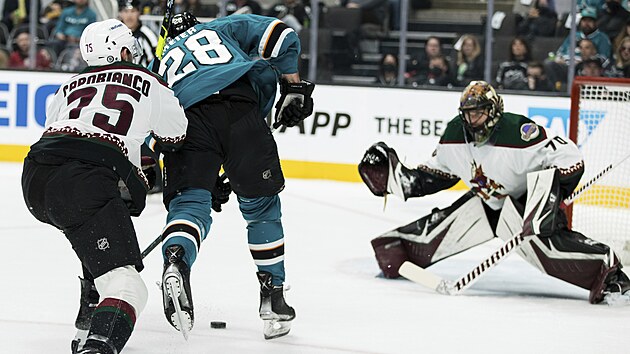Timo Meier ze San Jose bráněný Kylem Capobiancem z Arizony v šanci před brankářem Karlem Vejmelkou.