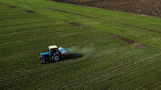 Traktor rozmet hnojivo na poli pobl ukrajinsk vesnice Jakovlivka.