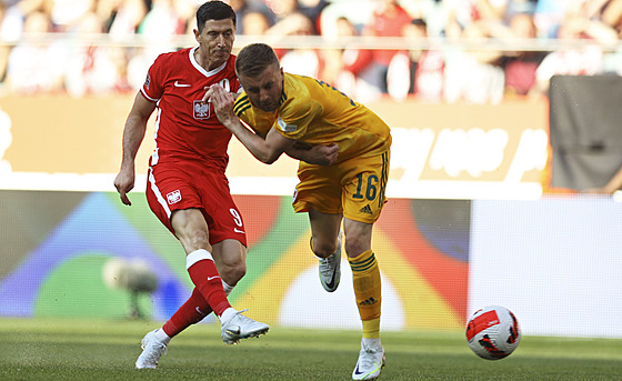 Polský fotbalista Robert Lewandowski (vlevo) stílí, bránit se mu v tom snaí...