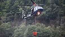 Policejní vrtulník pi práci na poáru v Národním parku eské výcarsko u...