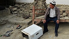Kyrgyz sedí u svého domu znieného po raketovém útoku Tádik.