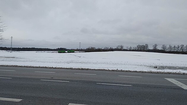 V zasněženém poli jsou vidět nákladní auta, která odvážejí ornici z trasy, kudy povede obchvat Lišova.