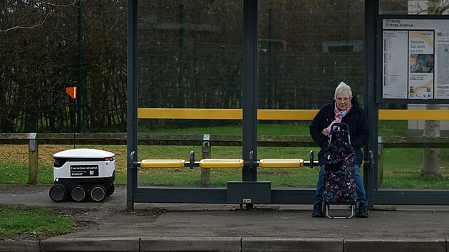 Osoba sed na autobusov zastvce pobl doruovacho robota v Sale v Britnii (21. bezna 2023)